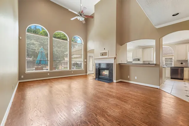 an empty room with wooden floor fireplace and windows