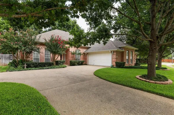 a front view of a house with a garden and tree