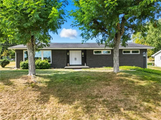 a view of a house with a yard and a large tree