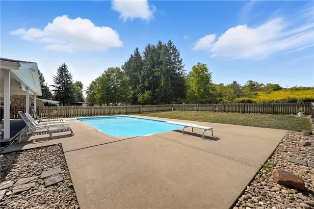 a view of swimming pool with lounge chair and dinning table under an umbrella