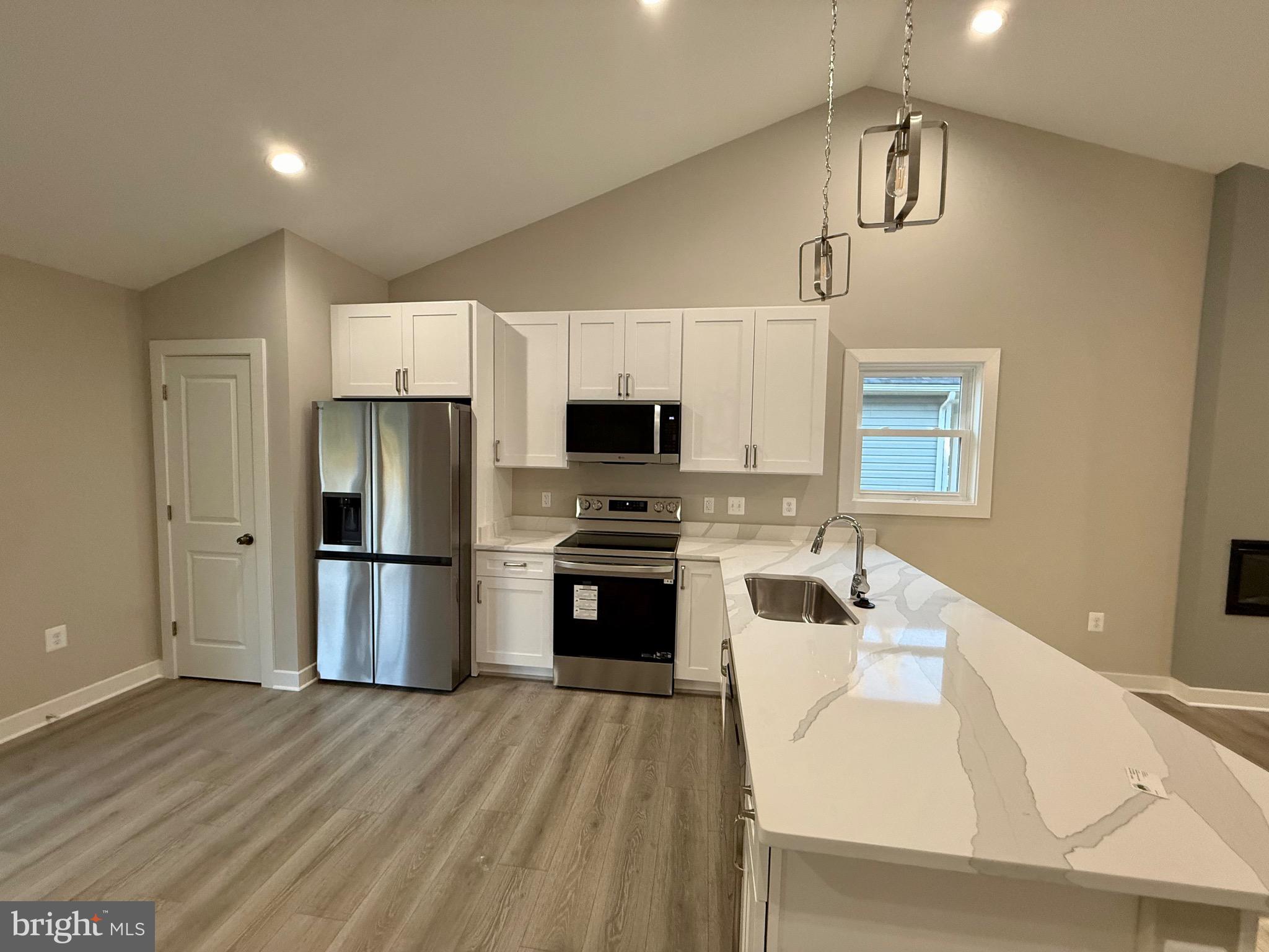 982 Mattox Avenue Colonial Beach, VA 22443 - Photo 11 of 53 a kitchen with a refrigerator a stove top oven a sink and dishwasher with wooden floor