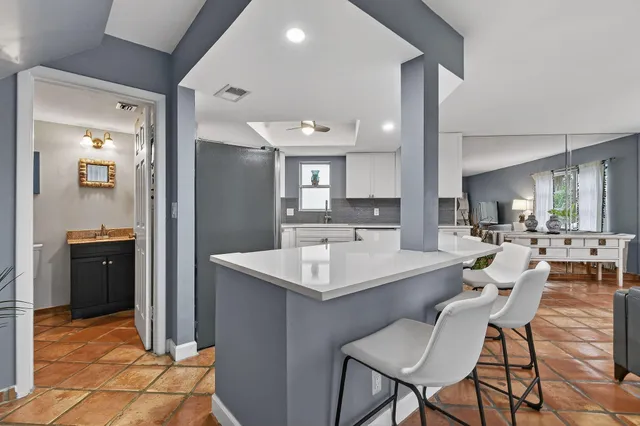 a living room with furniture a large window and kitchen view