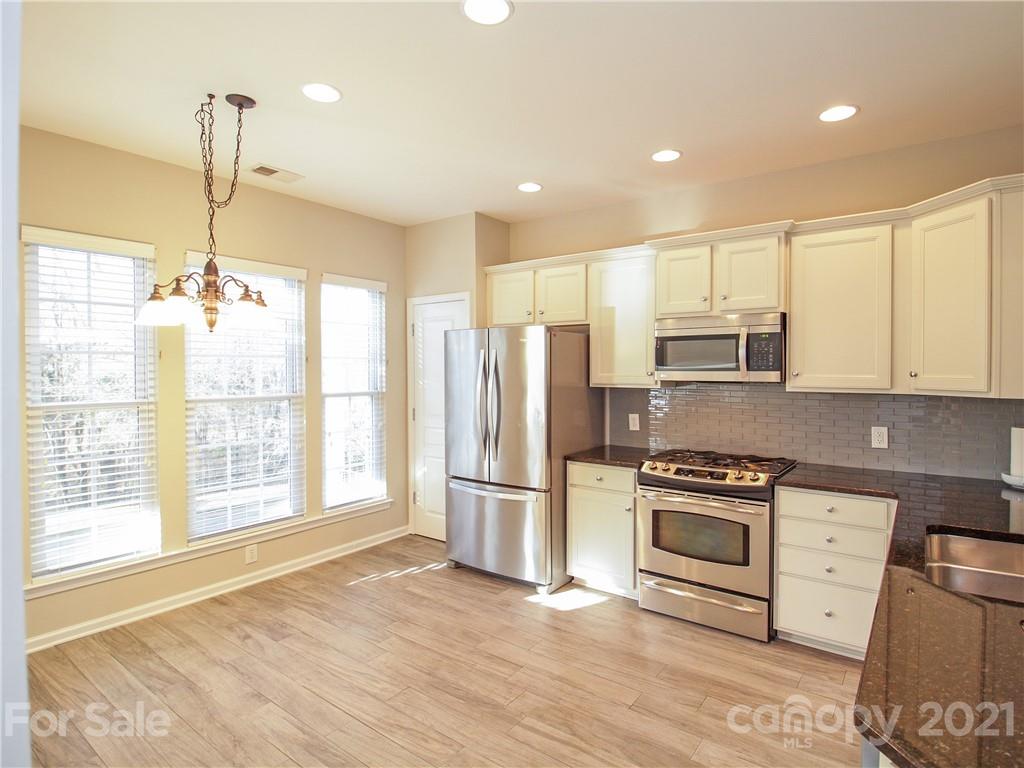 629 6th Baxter Crossing Fort Mill, SC 29708 - Photo 5 of 31 a kitchen with stainless steel appliances granite countertop a refrigerator a stove a sink dishwasher a oven with white cabinets and wooden floor