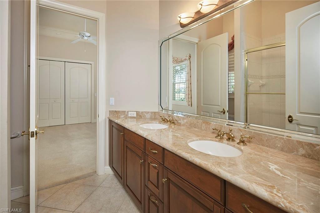 5669 Sago Court Naples, FL 34119 - Photo 19 of 41 Full Jack & Jill bath with double vanity, a shower stall, ceiling fan, and light tile floors