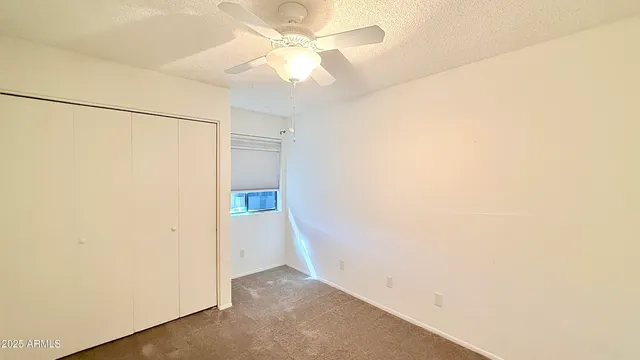 an empty room with a ceiling fan and a window