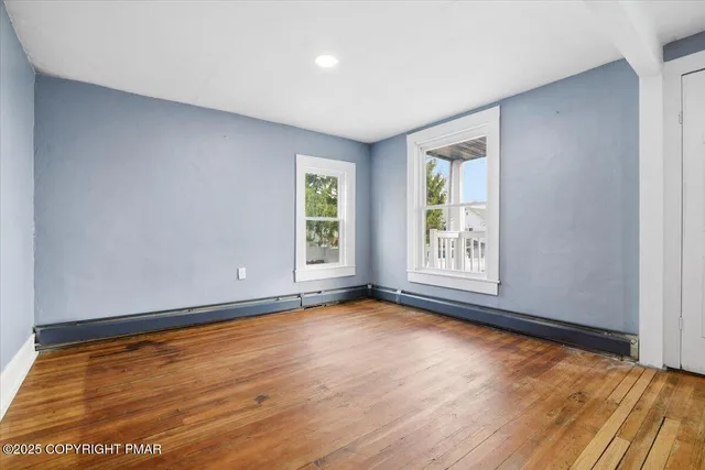 an empty room with a wooden floor and windows
