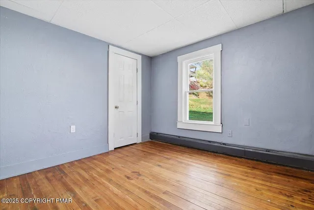 a view of an empty room with window and wooden floor