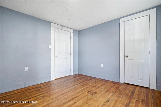 a view of an empty room with window and wooden floor