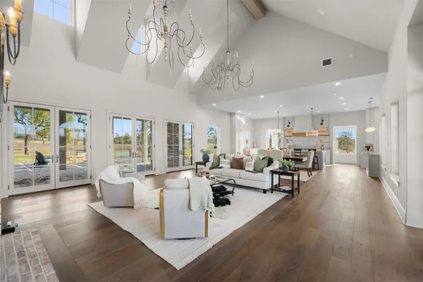 a kitchen with stainless steel appliances granite countertop a stove a refrigerator a kitchen island a dining table and chairs with wooden floor