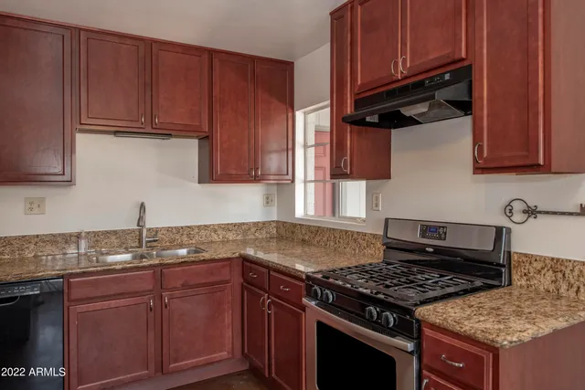 a kitchen with granite countertop stainless steel appliances a stove a sink dishwasher and cabinets with wooden floor