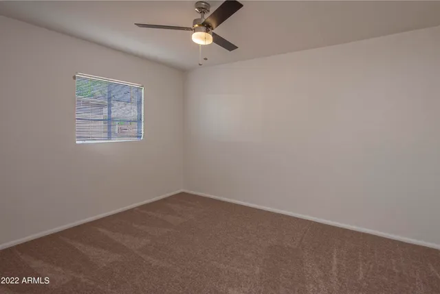 an empty room with a window and ceiling fan