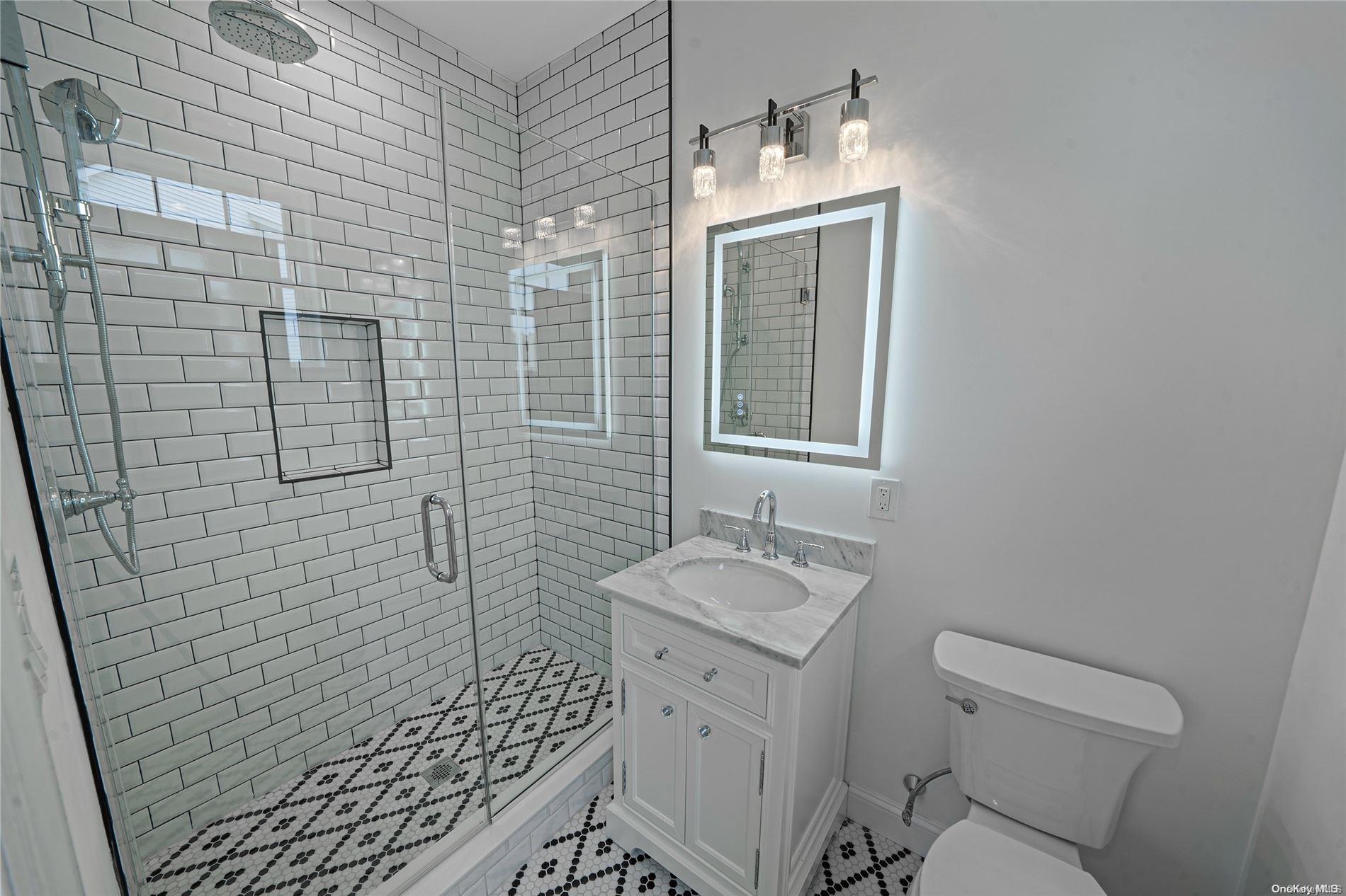 Lot 9 Sycamore Estates Nesconset, NY 11767 - Photo 27 of 35 a bathroom with a granite countertop white toilet a sink a shower and a mirror