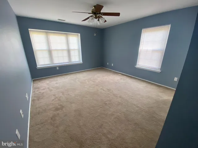 en empty room with windows and ceiling fan
