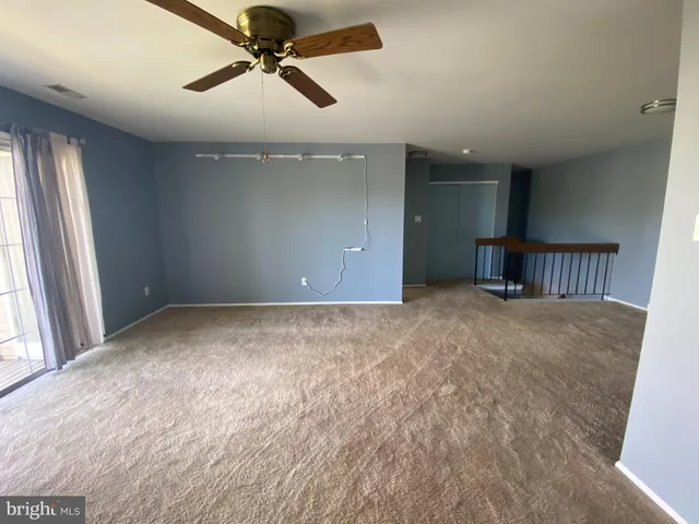 en empty room with windows and ceiling fan