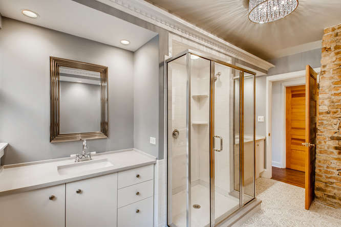 1429 West Roscoe Street Chicago, IL 60657 - Photo 18 of 65 a bathroom with a granite countertop sink a mirror and a shower