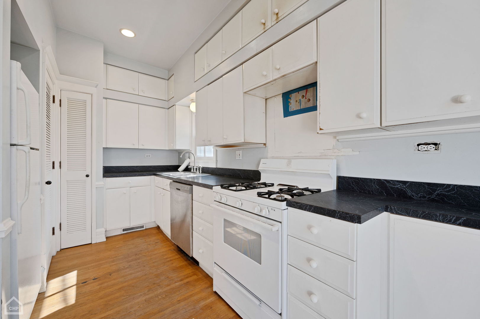 1429 West Roscoe Street Chicago, IL 60657 - Photo 48 of 65 a kitchen with granite countertop white cabinets and white appliances