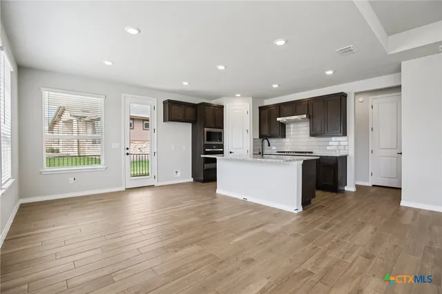 a large kitchen with stainless steel appliances kitchen island a large counter top and a wooden floor