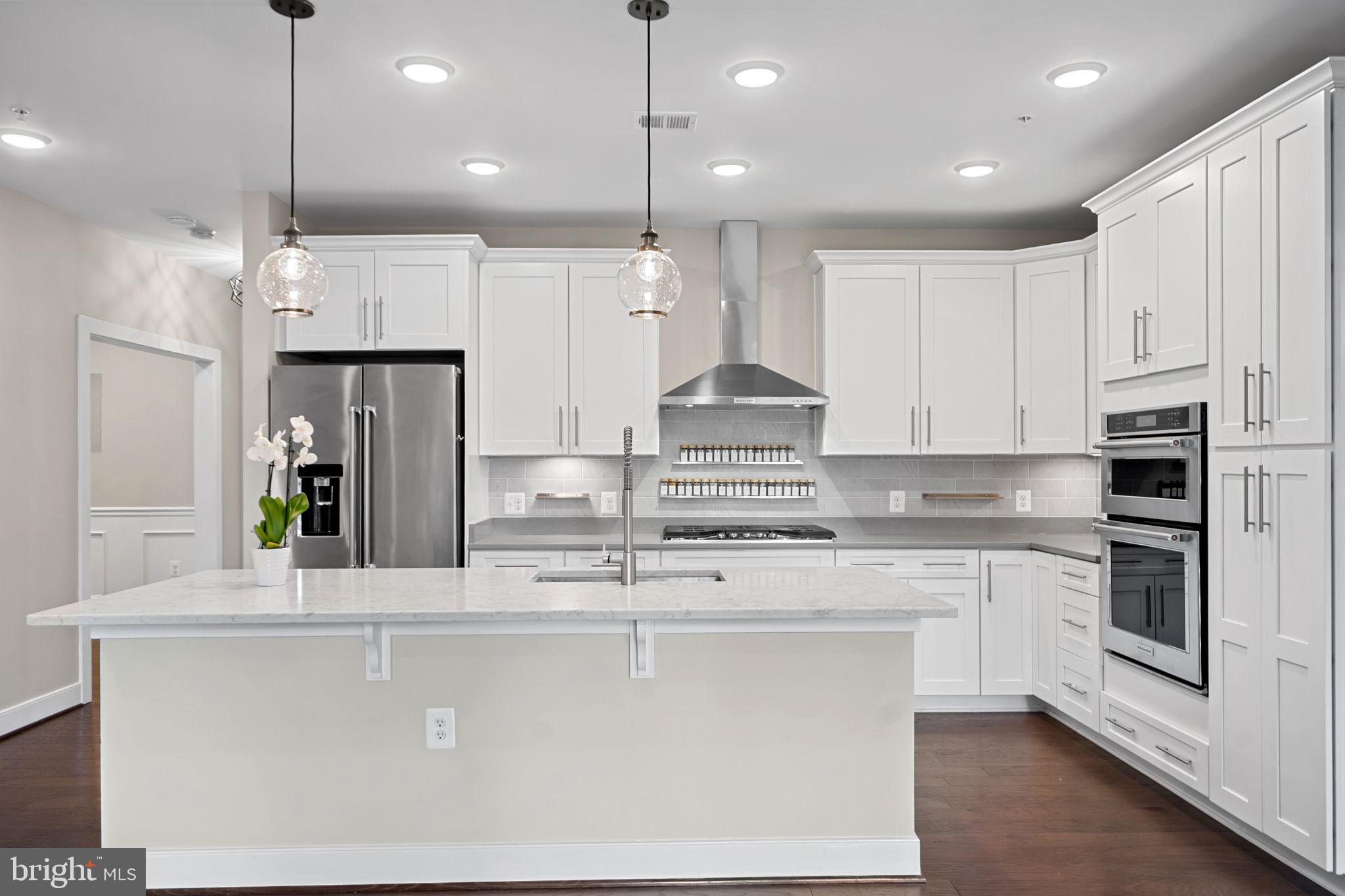 210 Decoverly Drive, Unit 106 Gaithersburg, MD 20878 - Photo 14 of 59 a kitchen with stainless steel appliances kitchen island granite countertop a stove a sink a refrigerator and white cabinets with wooden floor