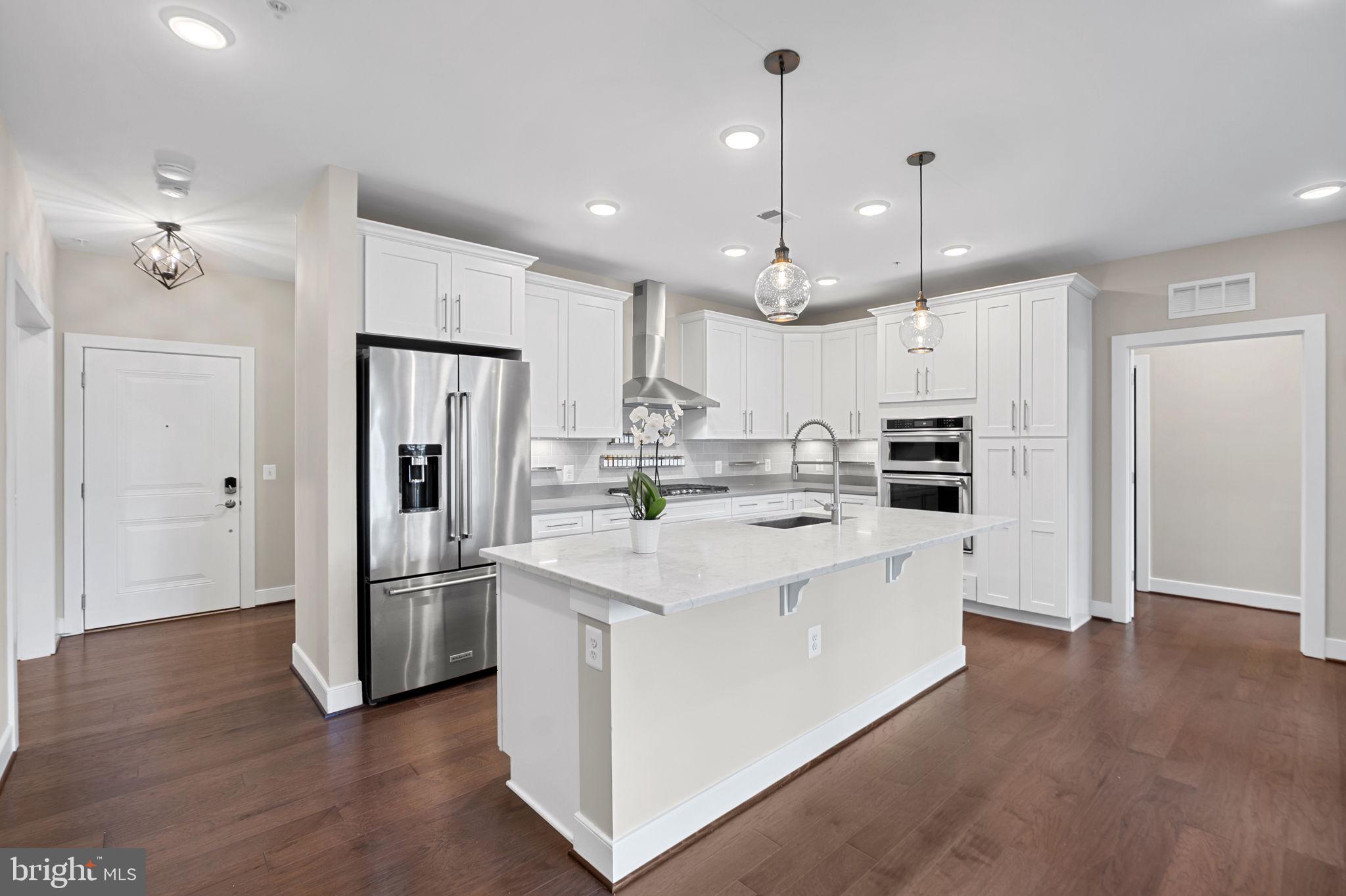 210 Decoverly Drive, Unit 106 Gaithersburg, MD 20878 - Photo 18 of 59 a kitchen with stainless steel appliances kitchen island a refrigerator a sink and wooden floor