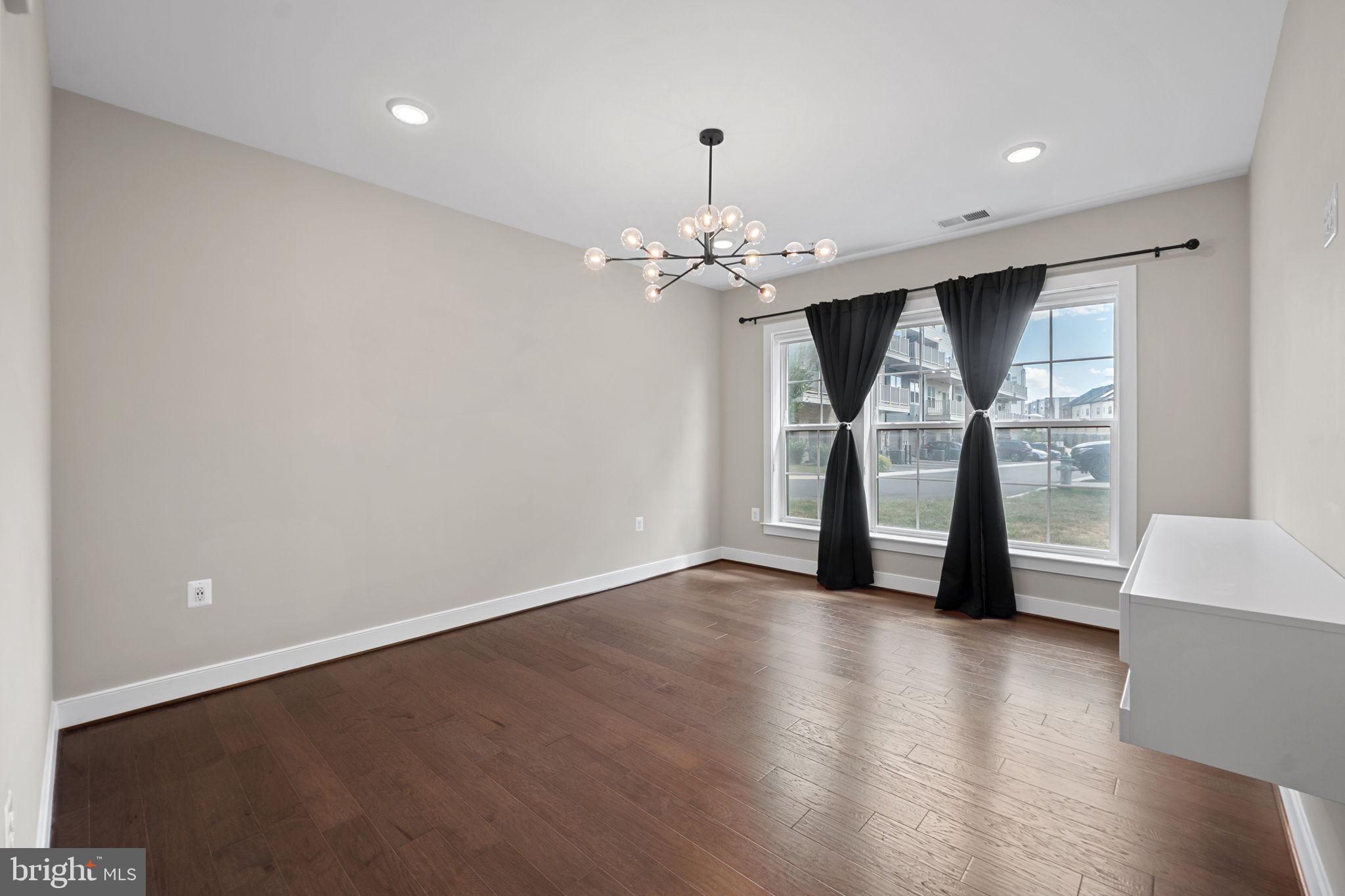 210 Decoverly Drive, Unit 106 Gaithersburg, MD 20878 - Photo 22 of 59 an empty room with wooden floor chandelier and windows