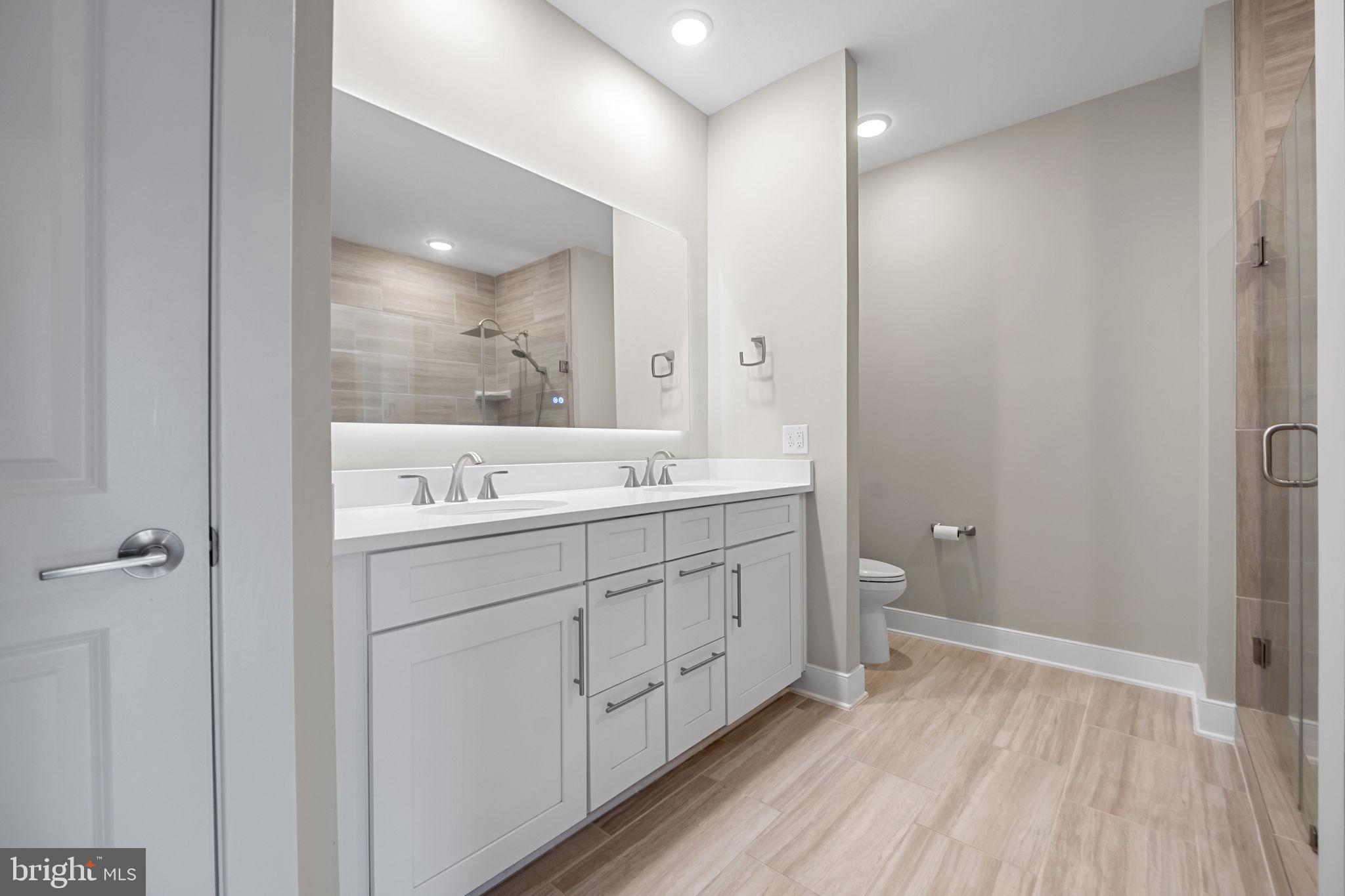 210 Decoverly Drive, Unit 106 Gaithersburg, MD 20878 - Photo 27 of 59 a bathroom with a double vanity sink and mirror with shower