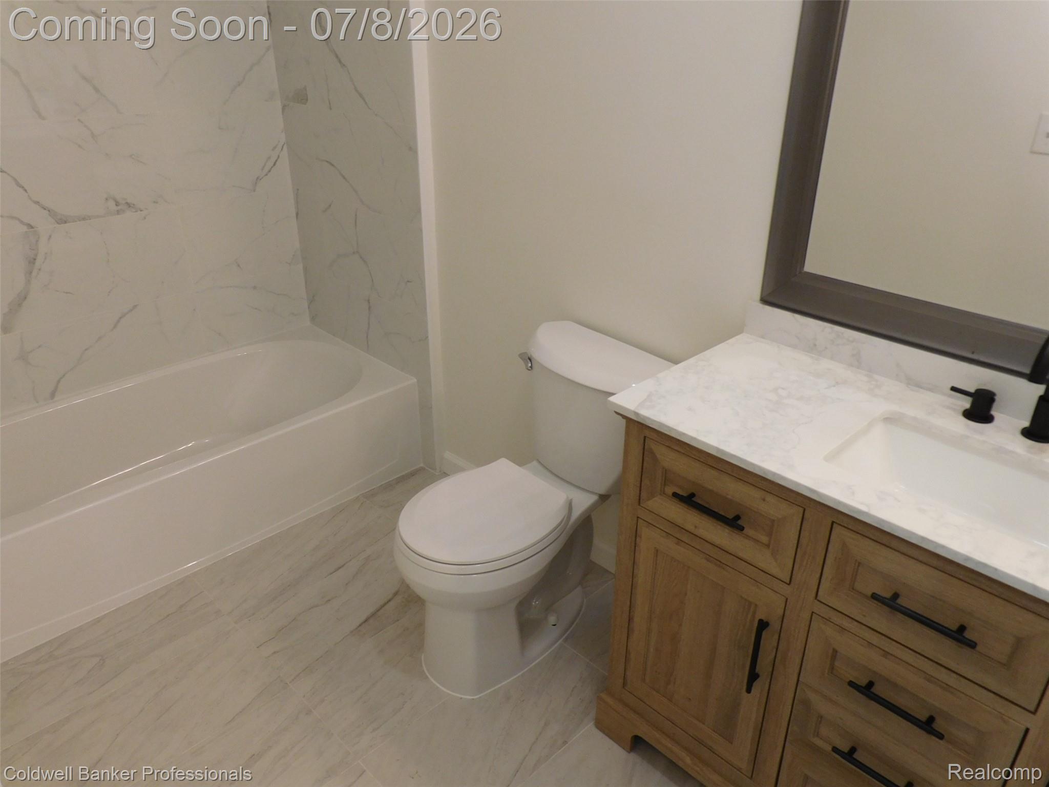 284 East 13 Mile Road Madison Heights, MI 48071 - Photo 18 of 21 Bathroom featuring a wood-finish vanity with a white countertop and integrated sink, matte black faucet, and framed mirror