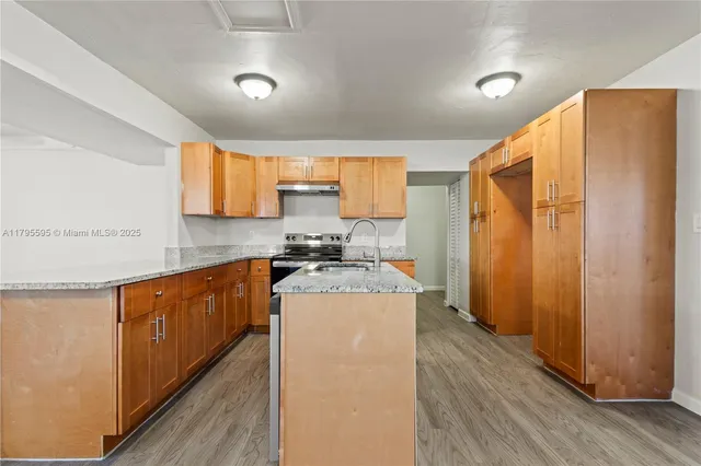 a kitchen with stainless steel appliances granite countertop wooden cabinets a sink and a refrigerator