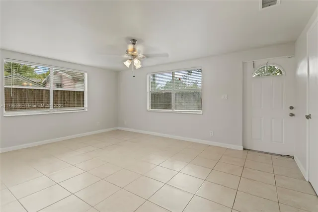 an empty room with windows and chandelier fan