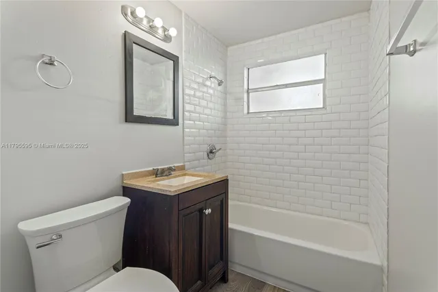 a bathroom with a granite countertop toilet a sink a mirror and bathtub