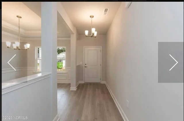 a view of a hallway with wooden floor and a large mirror
