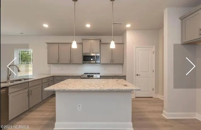 a large kitchen with granite countertop a sink a counter space appliances and cabinets