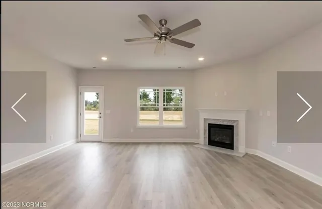 an empty room with wooden floor fireplace and windows