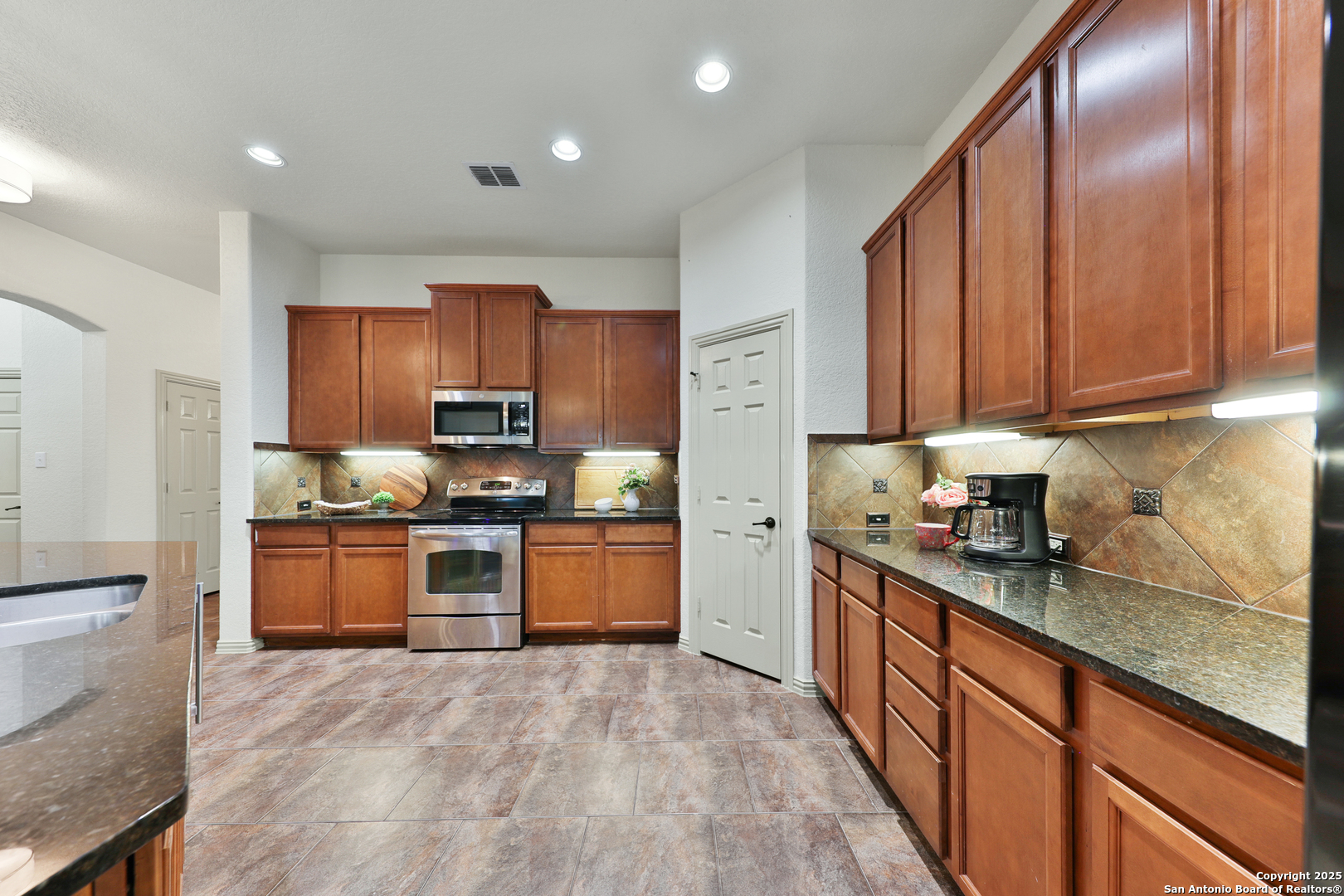 10811 Newcroft Place Helotes, TX 78023 - Photo 36 of 52 a kitchen with stainless steel appliances granite countertop a stove top oven a sink dishwasher a refrigerator and a cabinets with wooden floor