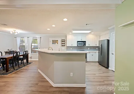 a large kitchen with stainless steel appliances granite countertop a stove a sink a refrigerator a dining table and chairs with wooden floor