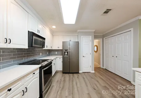 a kitchen with stainless steel appliances granite countertop a refrigerator a sink dishwasher a stove and white countertops with wooden floor