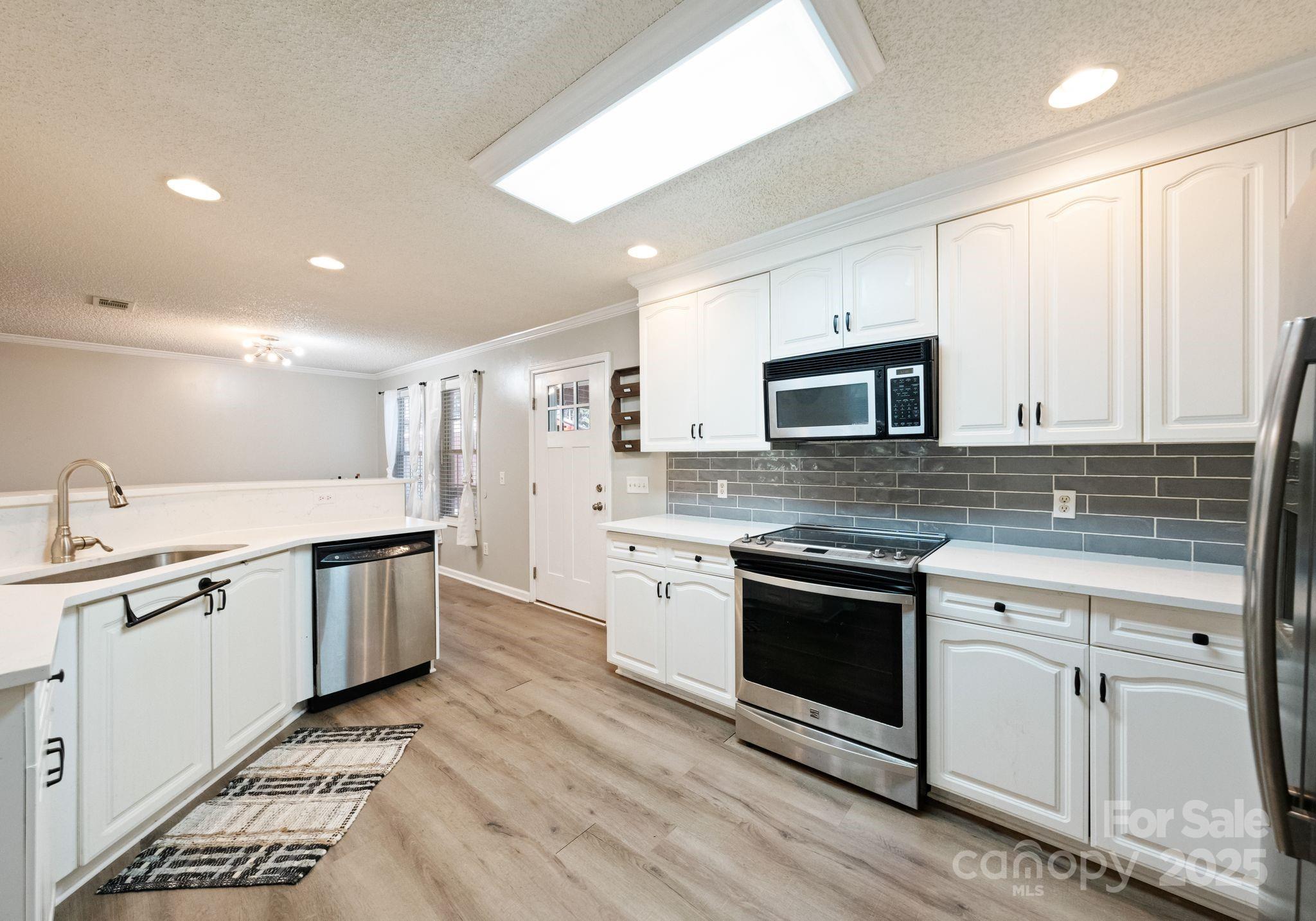 9951 Barnett Road Concord, NC 28027 - Photo 10 of 22 a kitchen with granite countertop white cabinets stainless steel appliances and sink