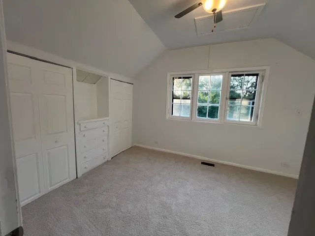 an empty room with a windows and chandelier fan