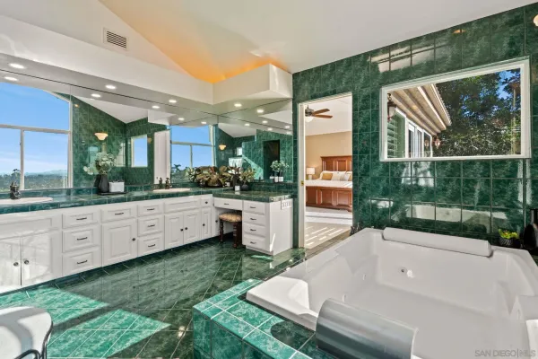 a bathroom with a bathtub and a sink mirror next to a window