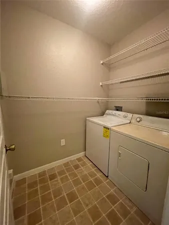 an empty room with a chandelier fan and windows