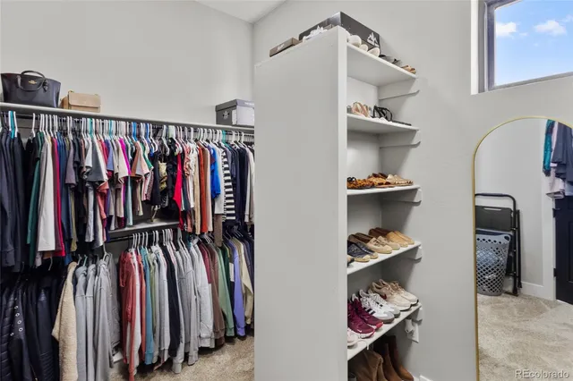a view of walk in closet with clothes and shoes