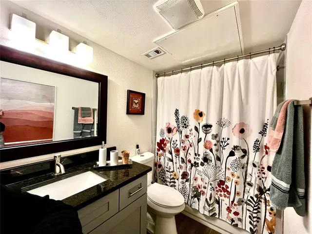 a bathroom with a granite countertop sink and a mirror with toilet