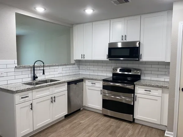 a kitchen with granite countertop a sink cabinets and wooden floor