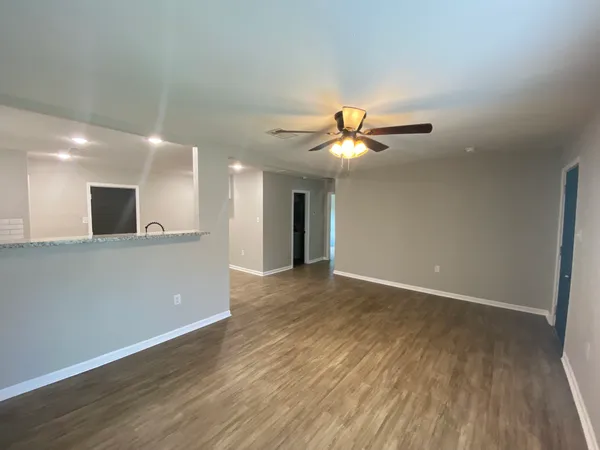 a view of an empty room with window and wooden floor