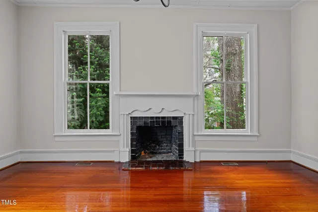 a view of empty room with wooden floor and a window