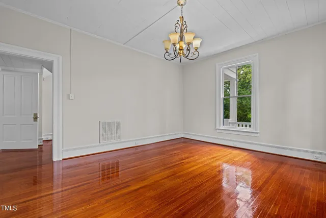a view of an empty room with wooden floor fireplace and a window