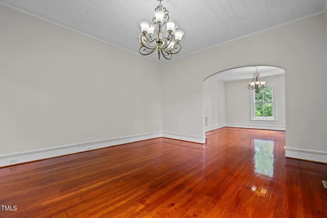 a view of an empty room with wooden floor fireplace and a window