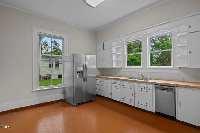 a view of an empty room with wooden floor and a fireplace