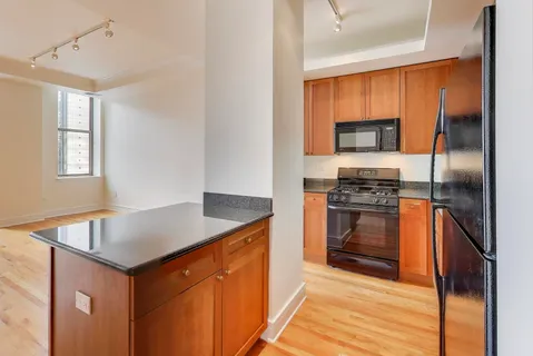 a kitchen with granite countertop a stove top oven and cabinets