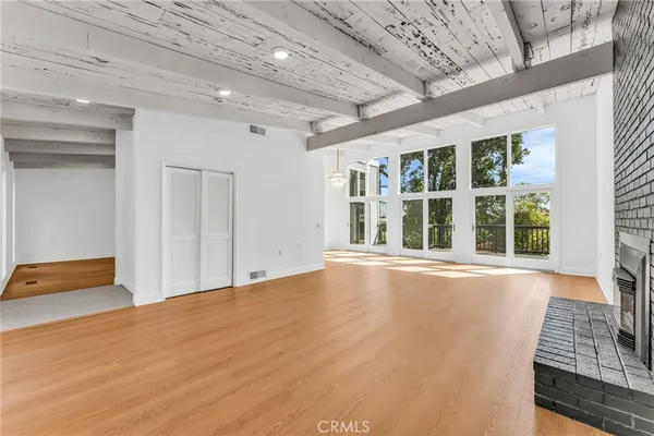 a room with stainless steel appliances kitchen island granite countertop a refrigerator a stove a sink and white cabinets with wooden floor