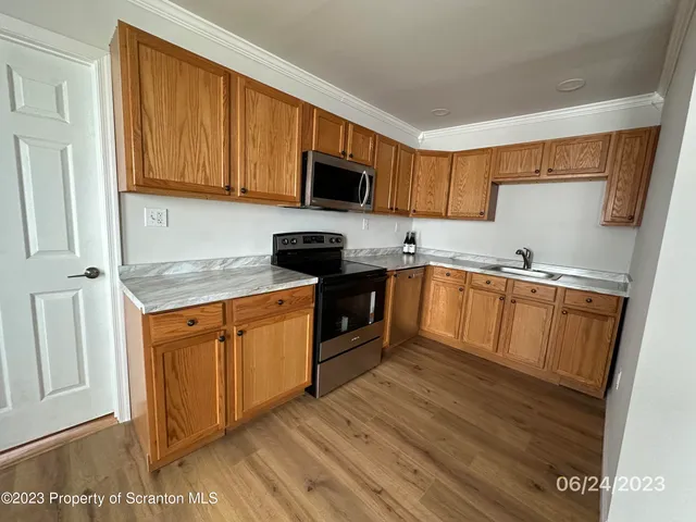 a kitchen with granite countertop wooden cabinets stainless steel appliances and a sink